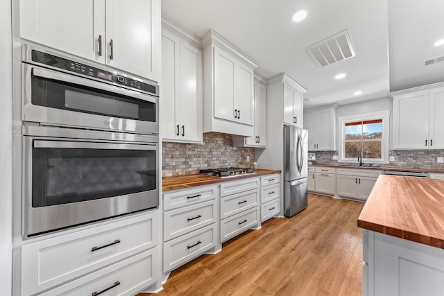 kitchen featuring white cabinetry, light hardwood / wood-style flooring, butcher block counters, and stainless steel appliances