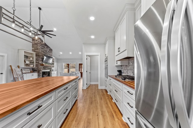 kitchen with white cabinets, butcher block counters, stainless steel appliances, and a fireplace