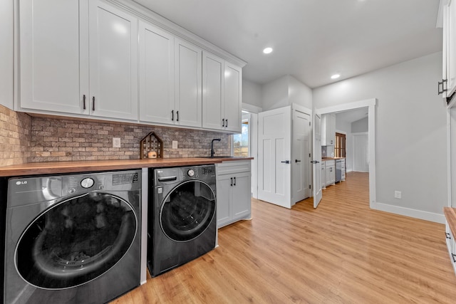 laundry room featuring cabinets, light hardwood / wood-style floors, independent washer and dryer, and sink