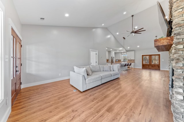 living room with high vaulted ceiling, french doors, ceiling fan, and light hardwood / wood-style floors