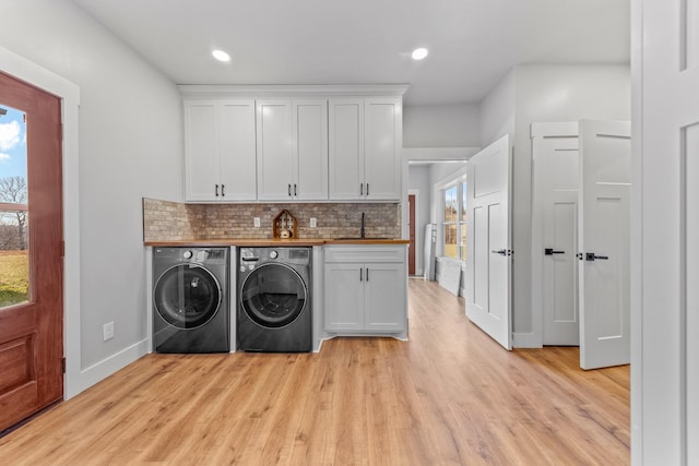 laundry area featuring light hardwood / wood-style floors, sink, cabinets, and independent washer and dryer