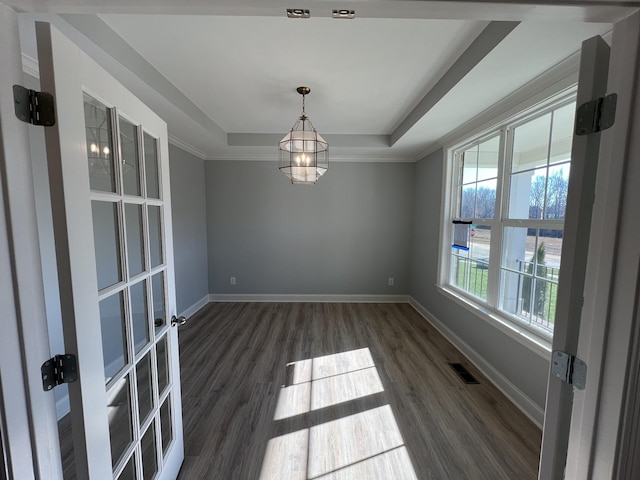 empty room featuring a raised ceiling, dark hardwood / wood-style flooring, and ornamental molding