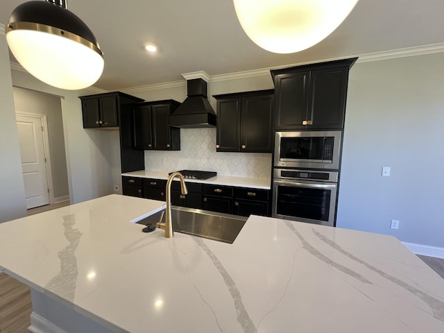 kitchen featuring sink, light stone countertops, an island with sink, appliances with stainless steel finishes, and custom range hood