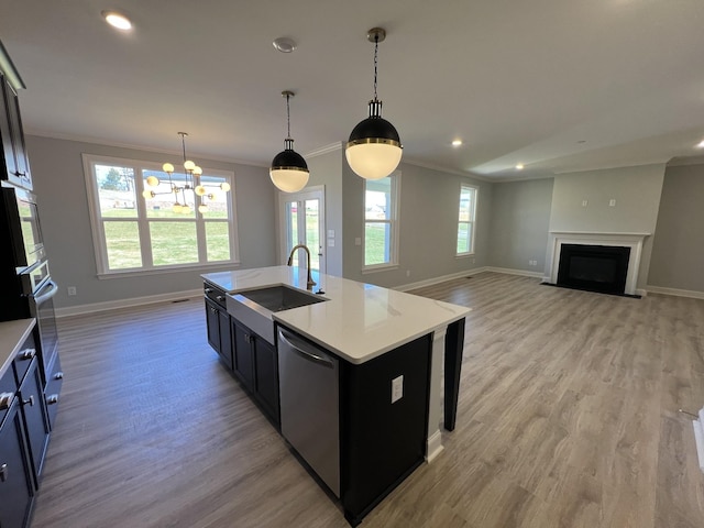 kitchen with dishwasher, sink, hanging light fixtures, light hardwood / wood-style flooring, and an island with sink