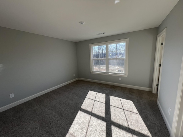 spare room featuring dark colored carpet