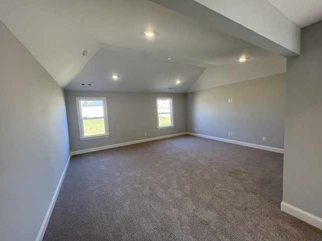 unfurnished room with dark carpet, a wealth of natural light, and lofted ceiling