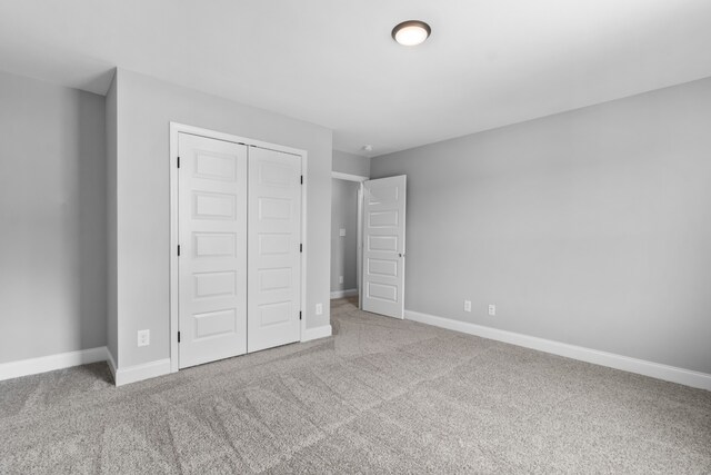 unfurnished bedroom with light colored carpet and a closet