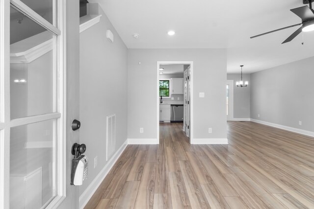 interior space featuring ceiling fan with notable chandelier and light hardwood / wood-style flooring