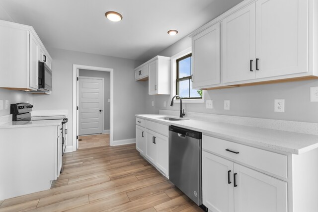 kitchen featuring light wood-type flooring, sink, dishwasher, range, and white cabinetry