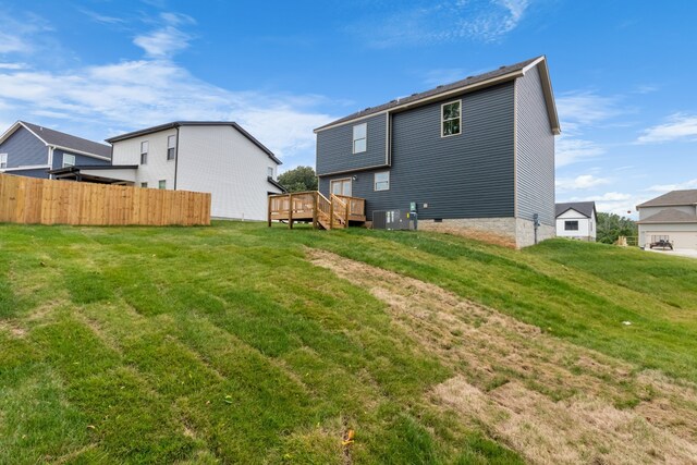 back of house with central air condition unit, a deck, and a lawn