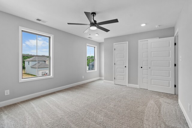 unfurnished bedroom featuring carpet flooring, ceiling fan, and two closets