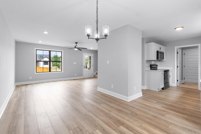 unfurnished living room featuring ceiling fan with notable chandelier and light hardwood / wood-style floors