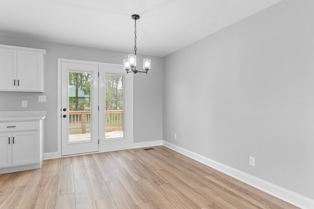 unfurnished dining area featuring light hardwood / wood-style floors and a notable chandelier