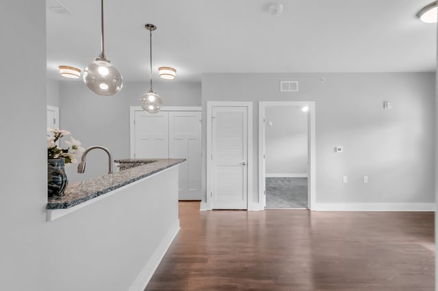 kitchen with light stone counters, dark hardwood / wood-style floors, and decorative light fixtures