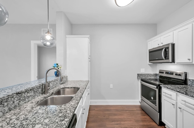 kitchen with white cabinetry, sink, light stone counters, dark hardwood / wood-style floors, and appliances with stainless steel finishes