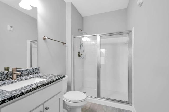 bathroom featuring toilet, a shower with door, vanity, and hardwood / wood-style flooring