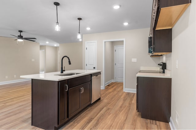 kitchen with sink, stainless steel dishwasher, light wood-type flooring, an island with sink, and decorative light fixtures