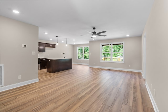 unfurnished living room with ceiling fan, light wood-type flooring, and sink