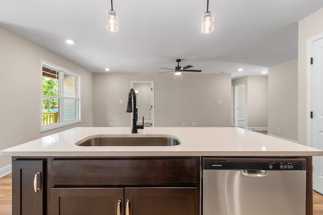 kitchen featuring sink, stainless steel dishwasher, decorative light fixtures, and light wood-type flooring