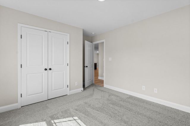 unfurnished bedroom featuring light carpet and a closet