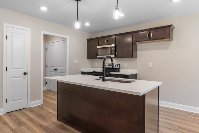 kitchen with sink, hanging light fixtures, stainless steel appliances, light hardwood / wood-style flooring, and dark brown cabinets