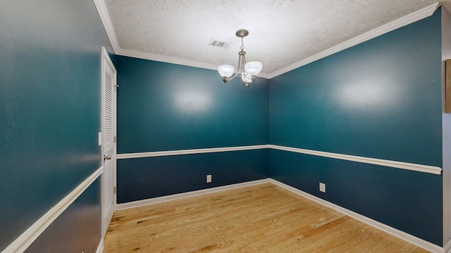 unfurnished room with a textured ceiling, hardwood / wood-style flooring, an inviting chandelier, and ornamental molding