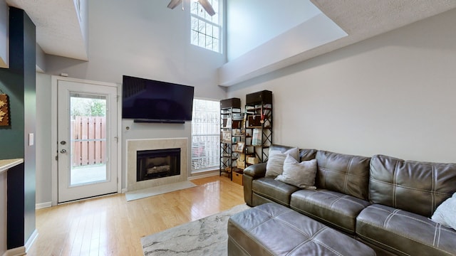 living room featuring a textured ceiling, light wood-type flooring, and ceiling fan