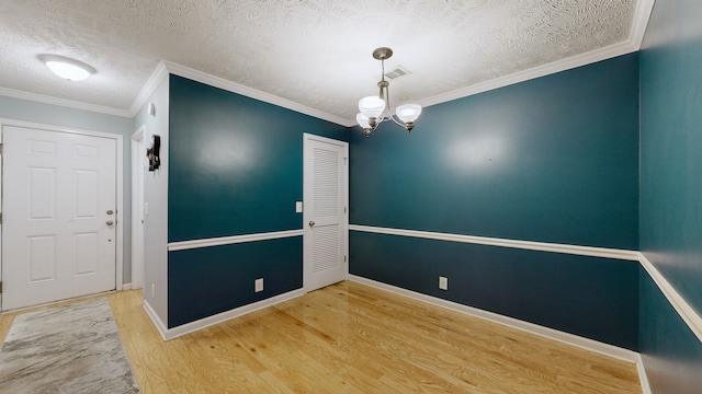 spare room featuring a notable chandelier, crown molding, wood-type flooring, and a textured ceiling