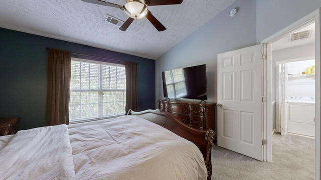 carpeted bedroom featuring washer / dryer, a textured ceiling, ensuite bathroom, and ceiling fan