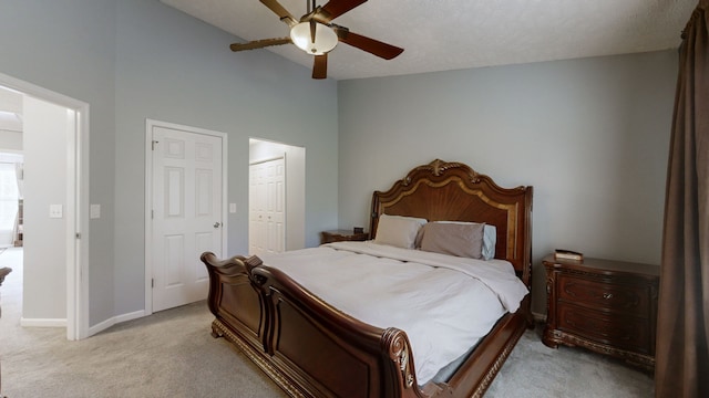 bedroom featuring light carpet, a textured ceiling, ceiling fan, a high ceiling, and a closet