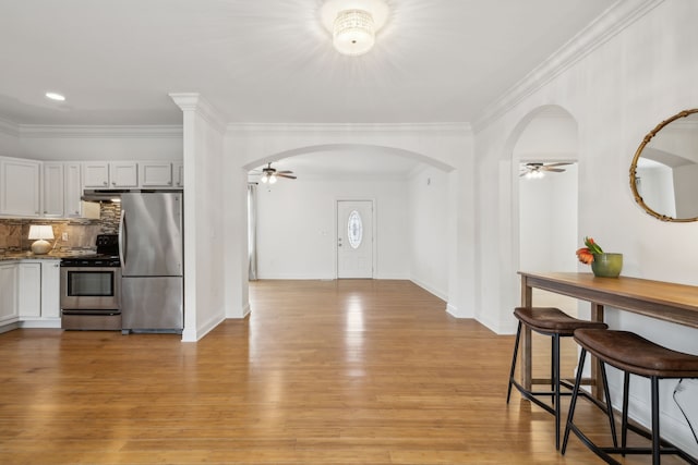 kitchen featuring ceiling fan, light hardwood / wood-style floors, appliances with stainless steel finishes, and tasteful backsplash