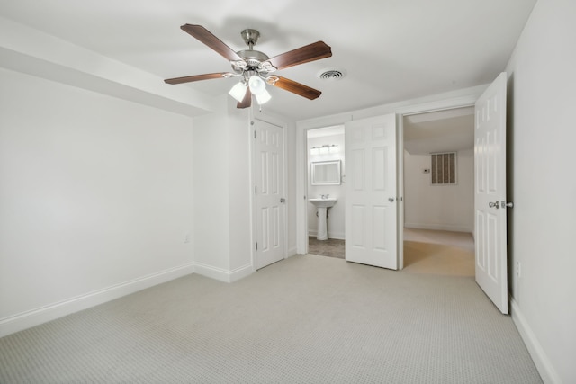 unfurnished bedroom with ceiling fan, ensuite bathroom, and light carpet