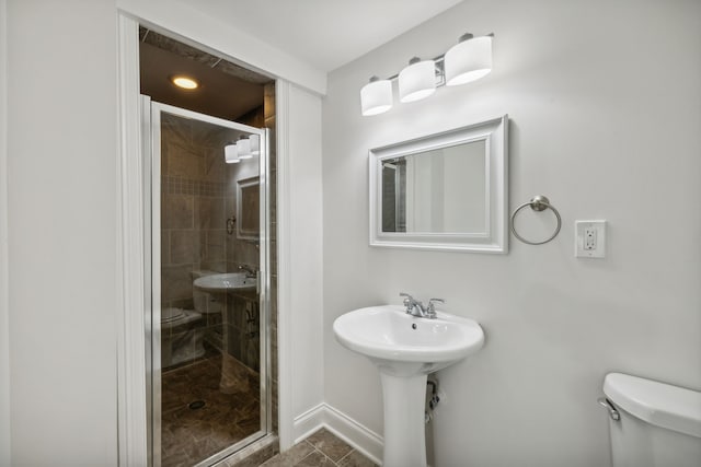 bathroom featuring toilet and a shower with shower door