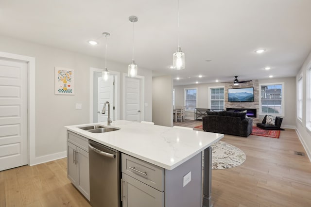 kitchen featuring decorative light fixtures, a center island with sink, sink, and dishwasher