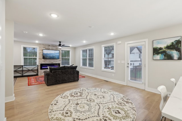 living room featuring a fireplace, light hardwood / wood-style flooring, and ceiling fan