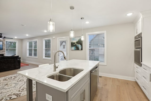 kitchen with appliances with stainless steel finishes, decorative light fixtures, white cabinetry, sink, and a kitchen island with sink