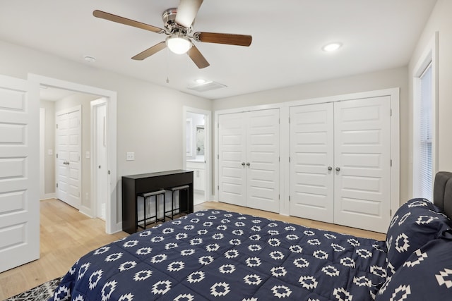 bedroom featuring ceiling fan, two closets, connected bathroom, and wood-type flooring