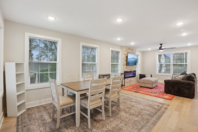 dining room featuring ceiling fan, wood-type flooring, and a fireplace