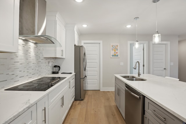 kitchen featuring wall chimney range hood, white cabinetry, appliances with stainless steel finishes, and sink