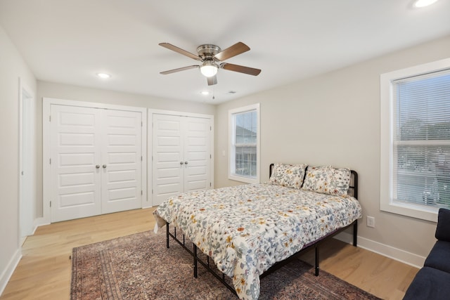 bedroom with wood-type flooring, multiple windows, two closets, and ceiling fan