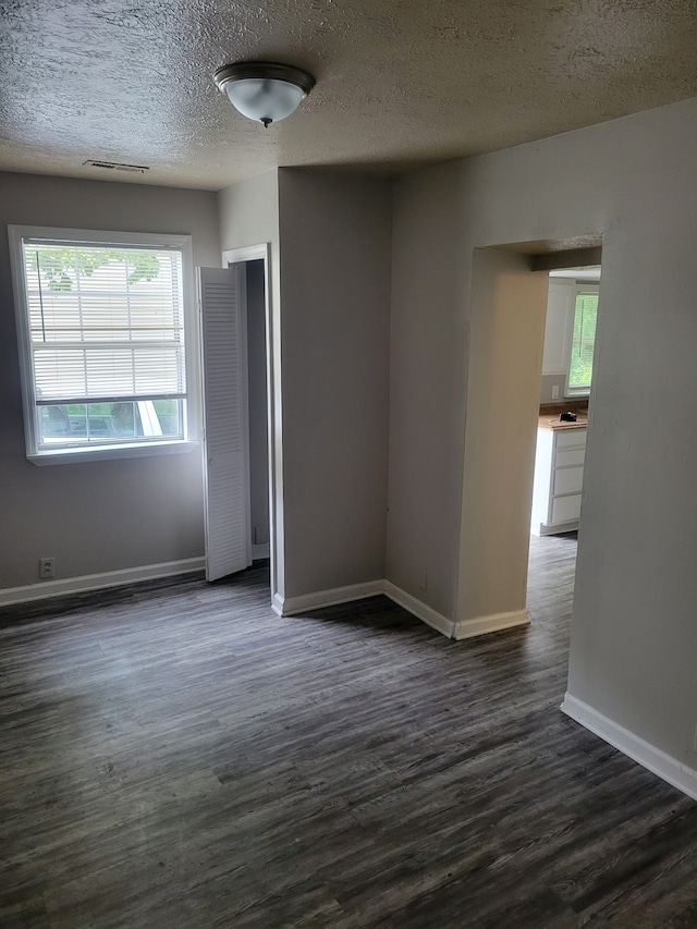 unfurnished room with dark hardwood / wood-style floors and a textured ceiling