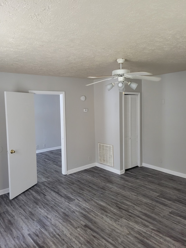 unfurnished room featuring a textured ceiling, ceiling fan, and dark wood-type flooring