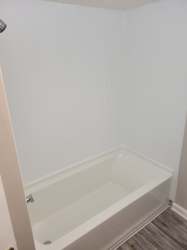 bathroom featuring wood-type flooring, a textured ceiling, and a tub