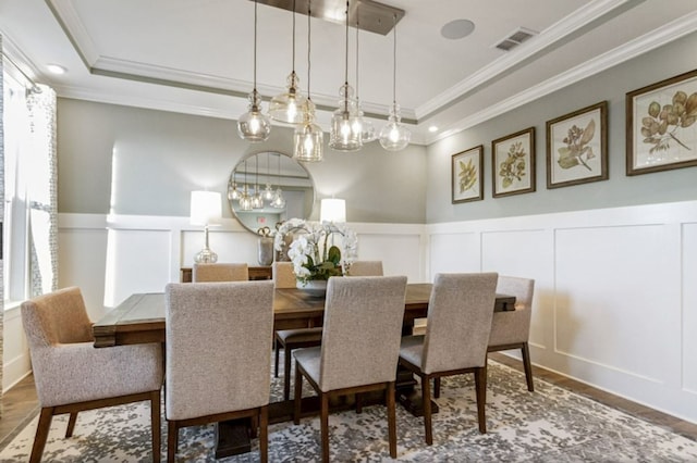 dining space featuring hardwood / wood-style floors, a notable chandelier, ornamental molding, and a tray ceiling