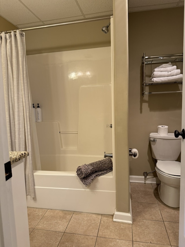 bathroom featuring tile patterned floors, a paneled ceiling, shower / bath combo with shower curtain, and toilet