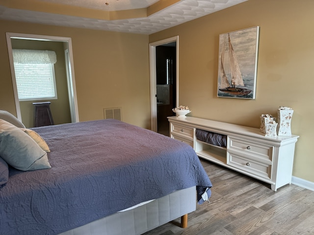 bedroom with a tray ceiling and light hardwood / wood-style flooring