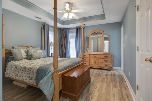 bedroom featuring ornamental molding, a tray ceiling, ceiling fan, and light hardwood / wood-style floors