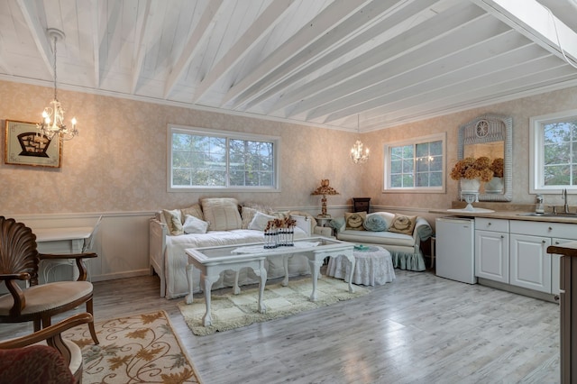 living room with beam ceiling, light hardwood / wood-style flooring, a notable chandelier, and sink