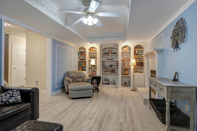 living room with ceiling fan, light wood-type flooring, built in features, and crown molding