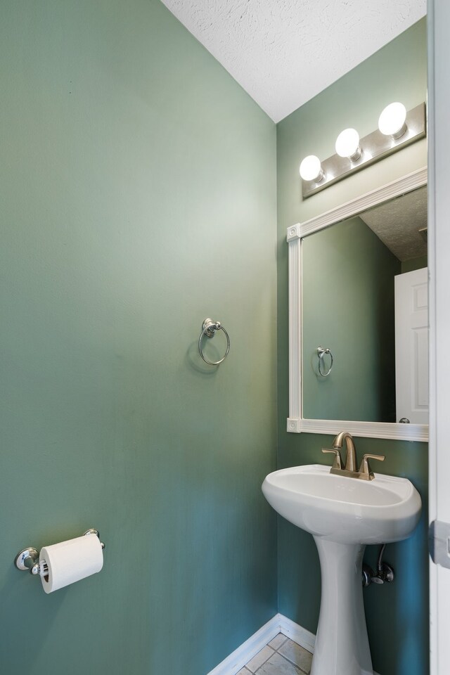 bathroom with tile patterned flooring, sink, and a textured ceiling